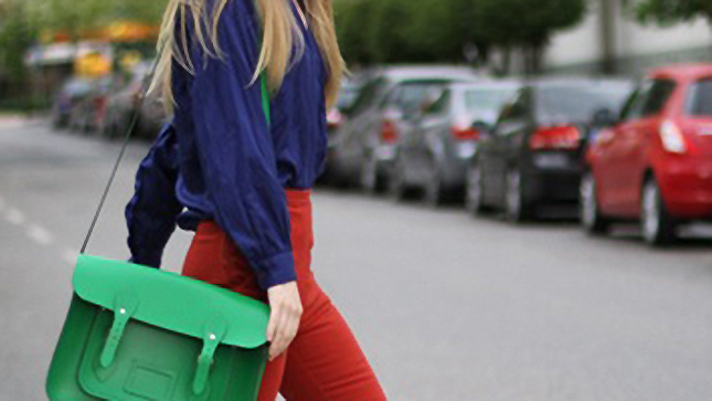 Foto detalhe de mulher usando blusa roxa e calça vermelha com bolsa verde