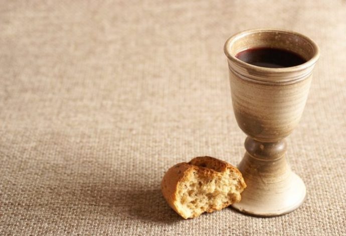 Foto de um calice de vinho e um pedaço de pão representando a páscoa